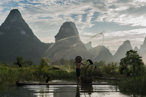 Cormoran fisherman throwing fishnet at dusk